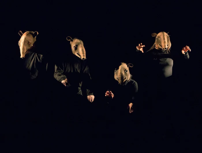 Four performers in Baku masks on a dark stage